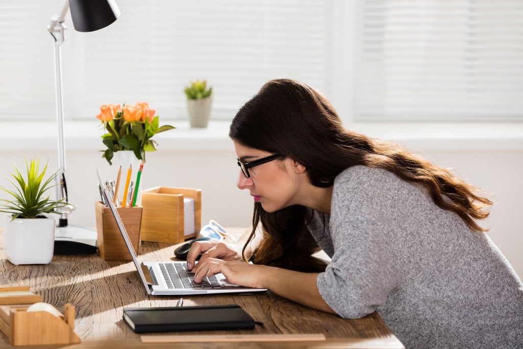 kobieta pracuje przed komputerem, niewłaściwa postawa, zmęczenie